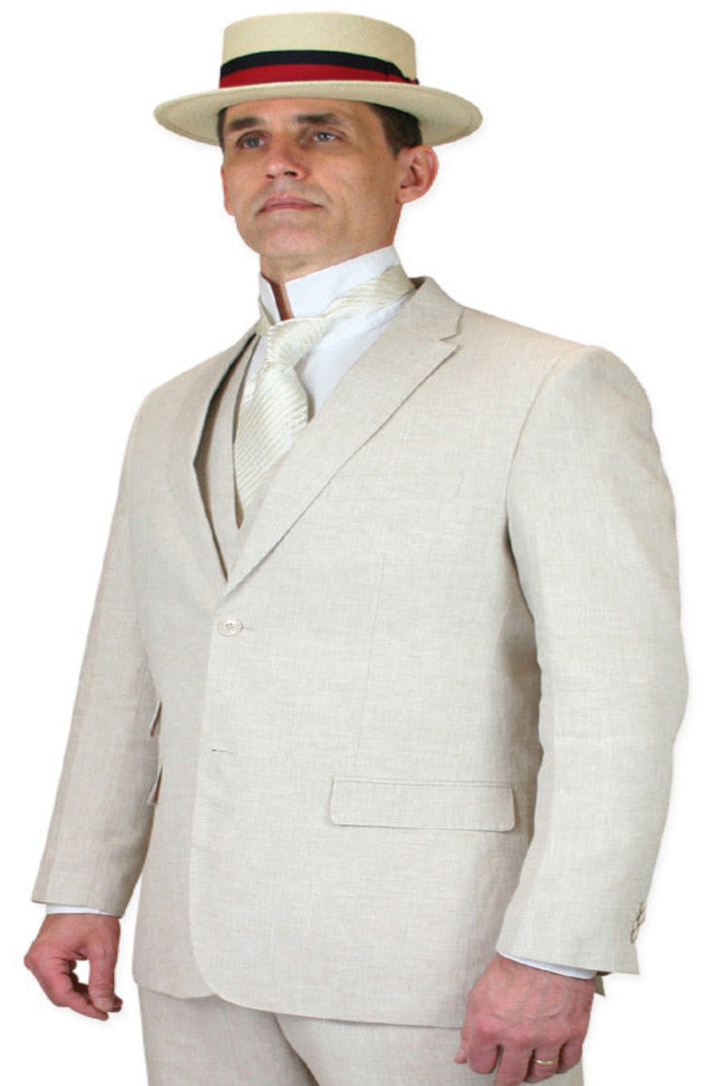 Natural beige linen three-piece suit (jacket, trousers) with white shirt and patterned tie. Textured fabric, ideal for summer. Model wears a straw hat with a red/black band.