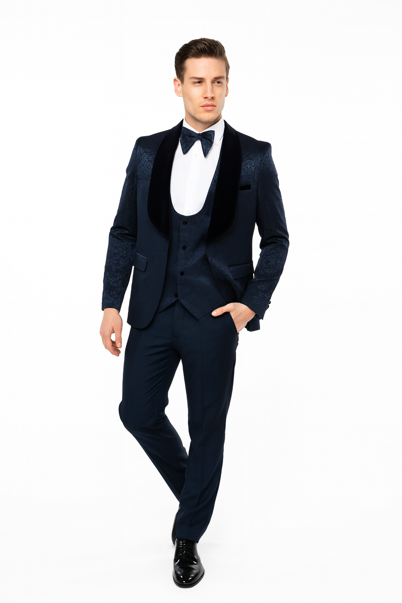 Navy jacquard tuxedo with black velvet shawl lapel. Tailored jacket, structured shoulders, fitted waist. Flat-front trousers. White shirt and bow tie complete the formal look.