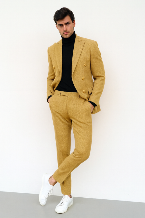 Gold double-breasted suit for men, featuring a fitted blazer with peaked lapels and tailored trousers. Textured gold fabric with a herringbone pattern. Blazer has side pockets and a matching waistline.