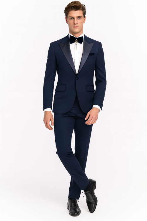 Navy blue tuxedo with satin peak lapel. Two-piece suit features a fitted blazer, tailored trousers, subtle patterned texture, and a navy bow tie. A cohesive formal look.