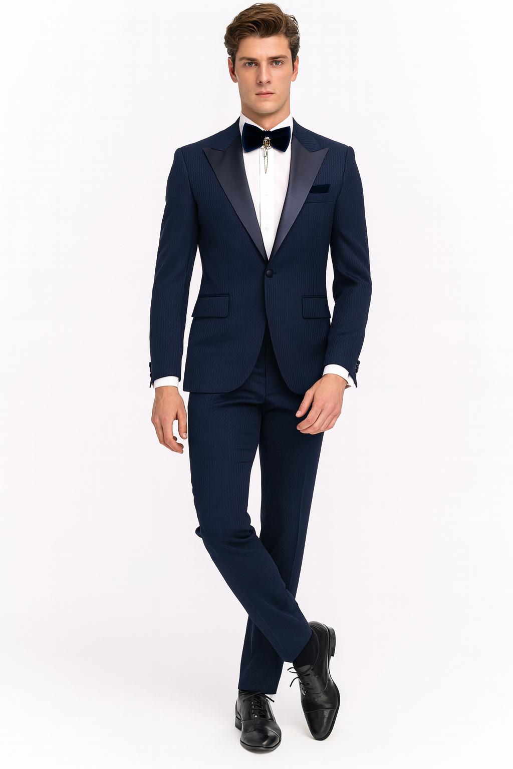 Navy blue tuxedo with satin peak lapel. Two-piece suit features a fitted blazer, tailored trousers, subtle patterned texture, and a navy bow tie. A cohesive formal look.