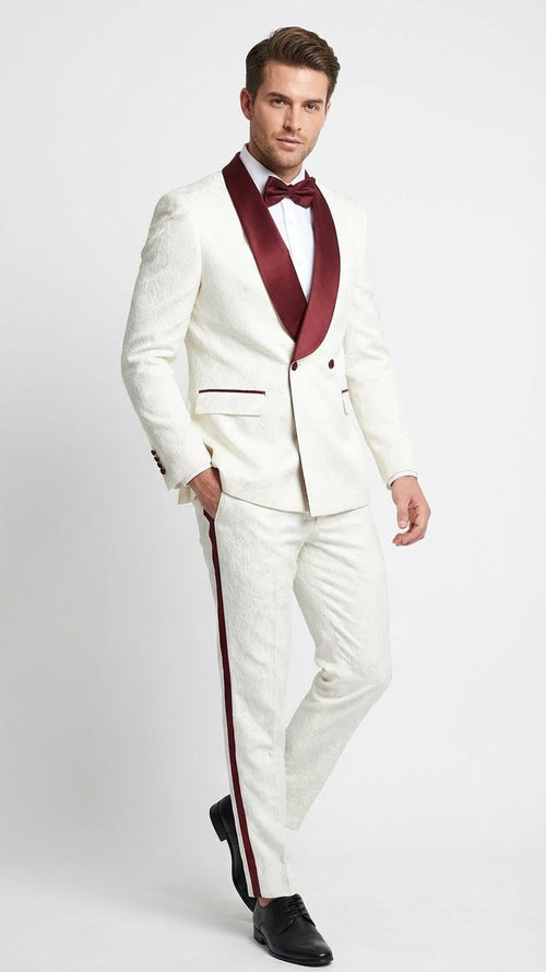 Ivory jacquard tuxedo suit with burgundy accents. Features a double-breasted blazer with shawl collar and piped pockets. Matching trousers with side stripes, and a burgundy bow tie.