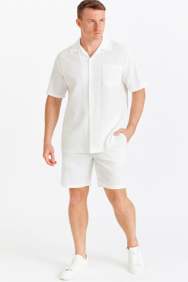 Men's white seersucker short set: lightweight, textured fabric. Includes a short-sleeved button-up shirt with a pocket and matching straight-cut shorts (above-knee hem). Shirt features a classic collar and rolled sleeves.