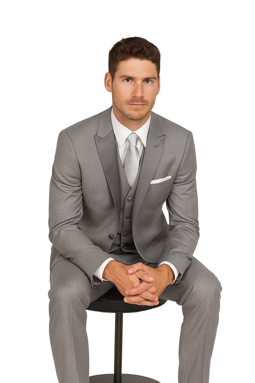 Grey tuxedo suit: fitted jacket w/ notch lapel, single button. Slim trousers. Smooth fabric. Paired w/ white dress shirt, light grey tie, and white pocket square. Tailored & structured formal look.