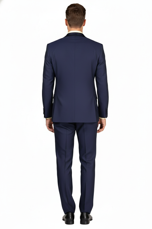Navy blue double-breasted tuxedo for men. Features satin peak lapel, structured fit, visible stitching, and smooth fabric. Deep navy color with a subtle texture. Tapered trousers.