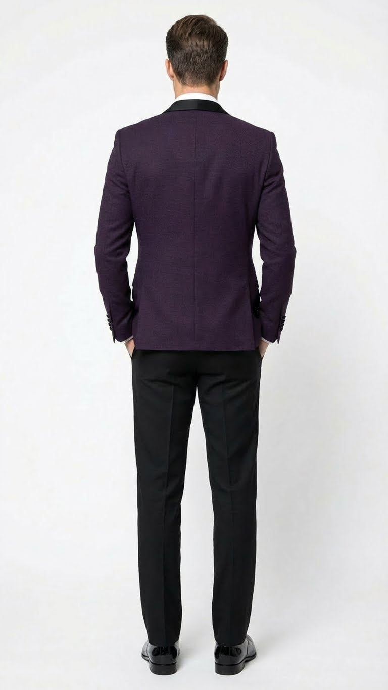 Men's eggplant purple tuxedo blazer with tailored fit, satin lapel, and textured fabric. Single vent back. Paired with black trousers.