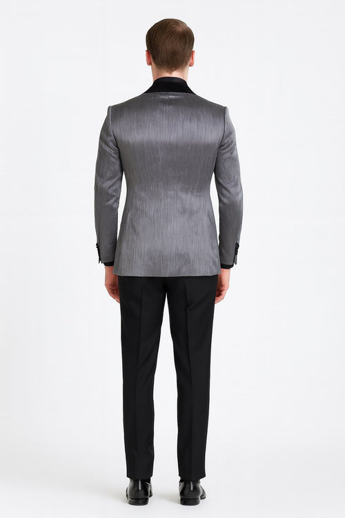Silver metallic tuxedo suit with black satin peak lapel. Fitted silhouette, textured surface, and structured shoulders. Black trousers enhance the formal design.