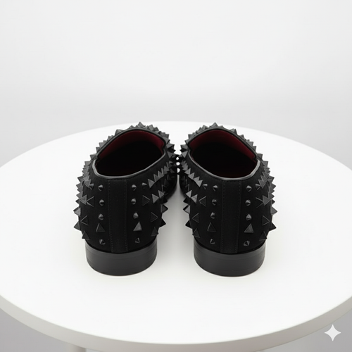 Men's black slip-on loafers with studded spikes. Smooth upper, rounded toe, and contrasting interior. Stylish and edgy design.