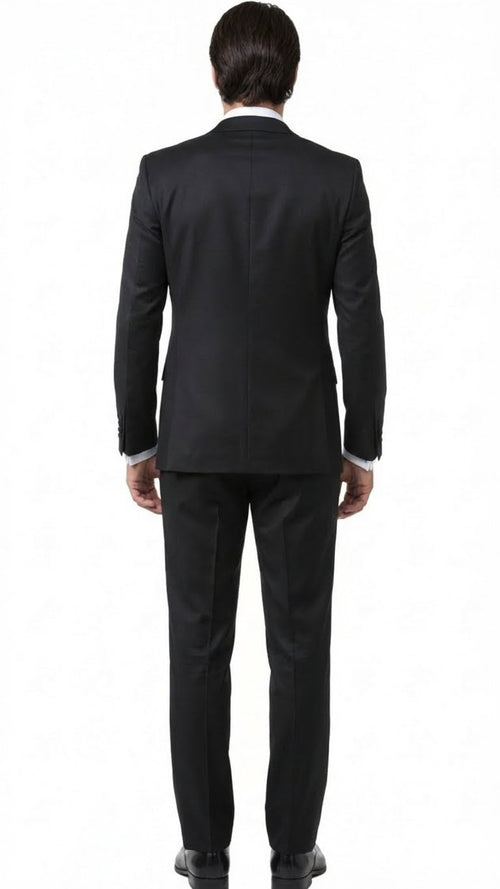 Black men's tuxedo suit viewed from the back. Fitted silhouette, structured design, smooth black fabric. Single vent jacket, matching trousers, and black shoes complete the formal look.