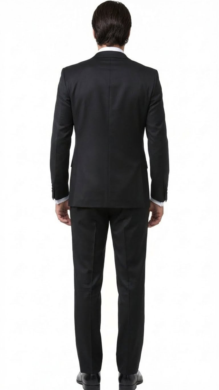 Black men's tuxedo suit viewed from the back. Fitted silhouette, structured design, smooth black fabric. Single vent jacket, matching trousers, and black shoes complete the formal look.