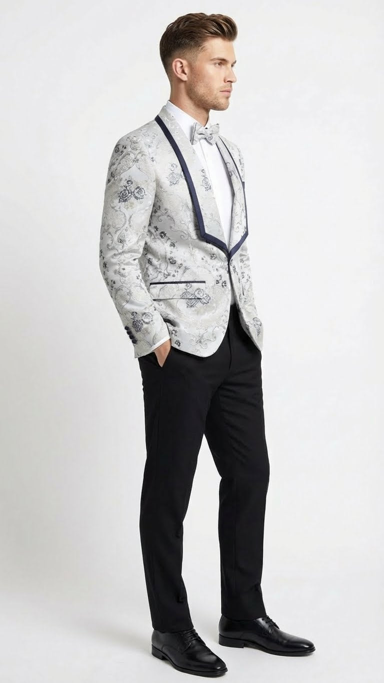 Men's white & navy floral jacquard blazer. Structured silhouette with contrast navy shawl lapel. Intricate blue floral pattern. Features navy-trimmed pockets. Paired with tailored black pants.