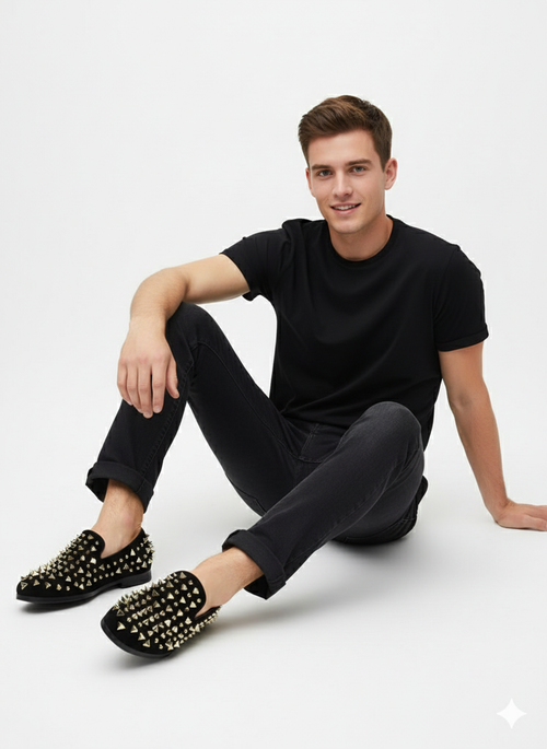 Men's black velvet loafers with rounded toe, studded with gold and silver spikes. Flat black soles complete the look.
