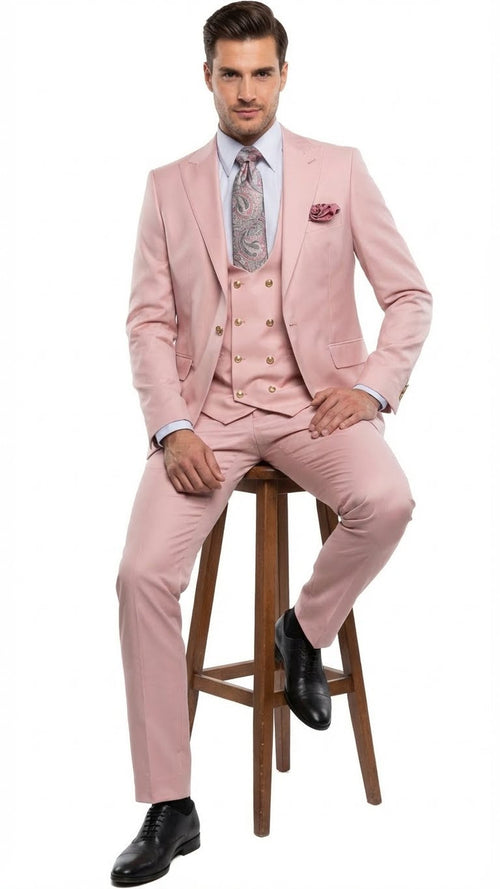 Blush pink three-piece men's suit with tailored jacket, waistcoat (gold buttons), and trousers. Features a slim fit, paired with a light blue shirt and patterned tie. Trousers extend to the shoes.