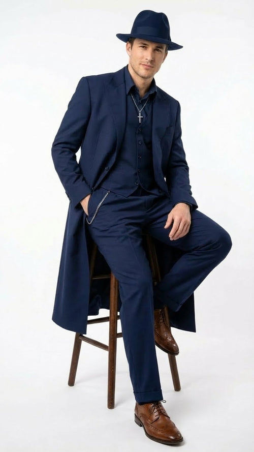 Navy 1920s zoot suit: fitted jacket, flowing silhouette, matching vest & tapered trousers. Navy hat & high-quality fabric sheen. Silver chain detail.