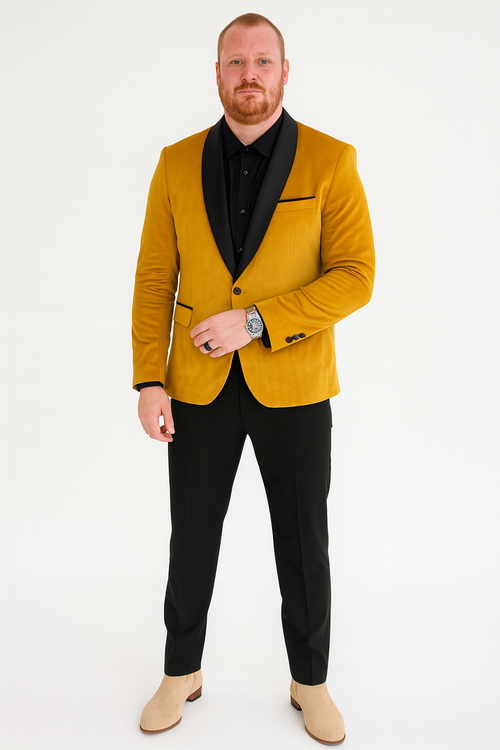 Mustard gold velvet tuxedo jacket with a fitted silhouette. Black satin shawl collar, single-button closure, and matching trim on the pocket. Smooth texture.