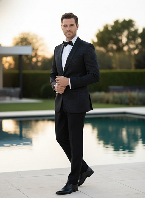 Men's black tuxedo suit with textured paisley floral pattern. Fitted silhouette includes matching pants, white shirt, and black bow tie. Subtle tonal variations in black.