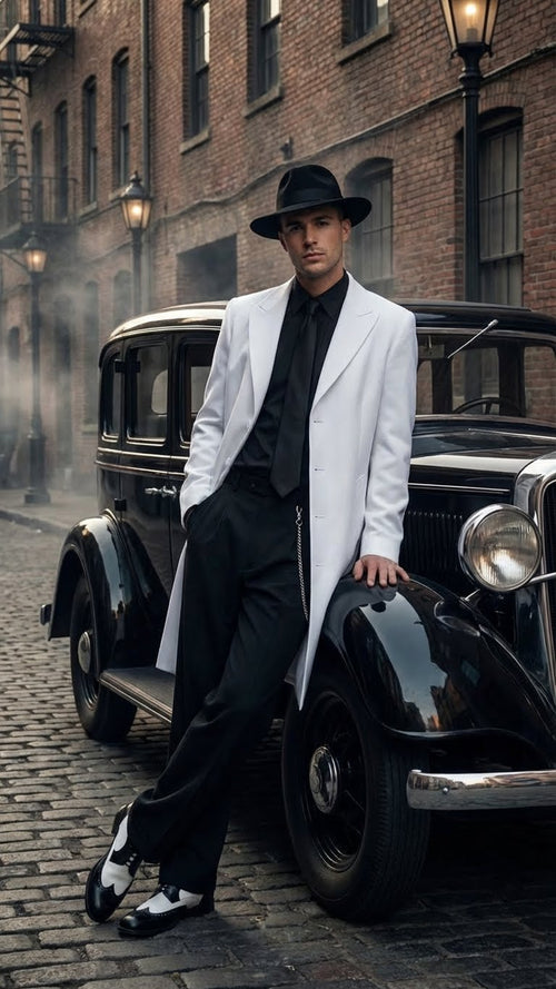 Men’s white zoot suit gangster style outfit features a long white jacket with a sharp lapel, paired with a black shirt and pants. The jacket has sleek tailoring and is complemented by black and white shoes.