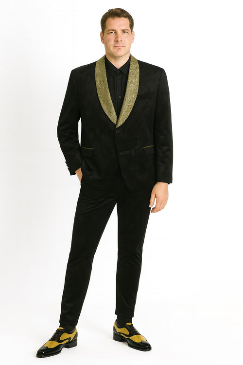 Black and gold jacquard tuxedo blazer. Features a textured black material with a gold jacquard pattern, shawl collar, fitted shape, two front pockets, and two-button closure with a shiny gold collar.