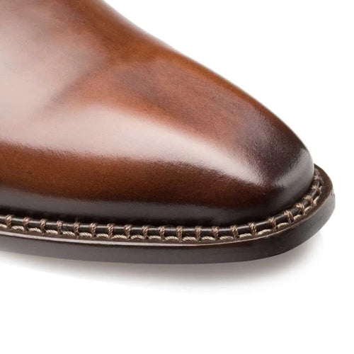Mezlan men's plain toe shoe. Brown, polished calfskin leather upper with a pointed toe. Decorative stitching on the sole edge. Streamlined, formal design.