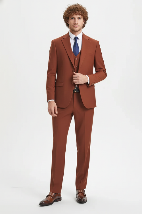 Men's rust brown three-piece suit. Fitted blazer with structured shoulders, three-button waistcoat, and tailored trousers. Smooth fabric with minimal texture.