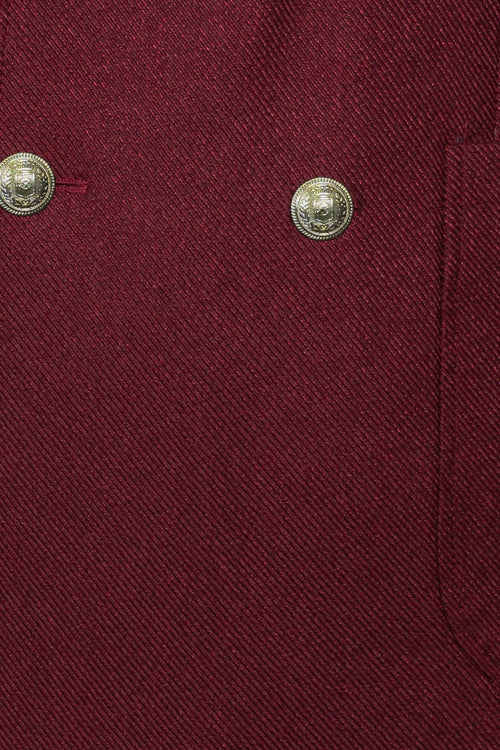 Men's burgundy slim-fit blazer with a sharp double-breasted design. Textured fabric with diagonal ribbing and gold buttons. Tailored structure.