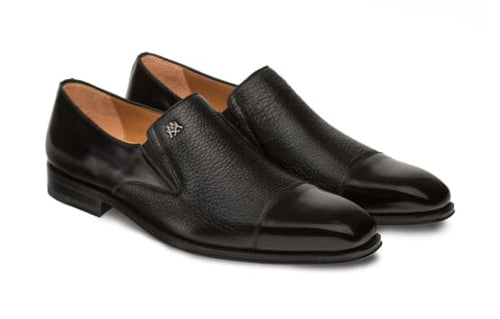 Milani slip-ons: black calfskin & deerskin. Rounded toe, glossy toe cap, matte sides. Metallic logo. Tan interior lining. Flat sole with subtle heel. Sleek, slip-on design.
