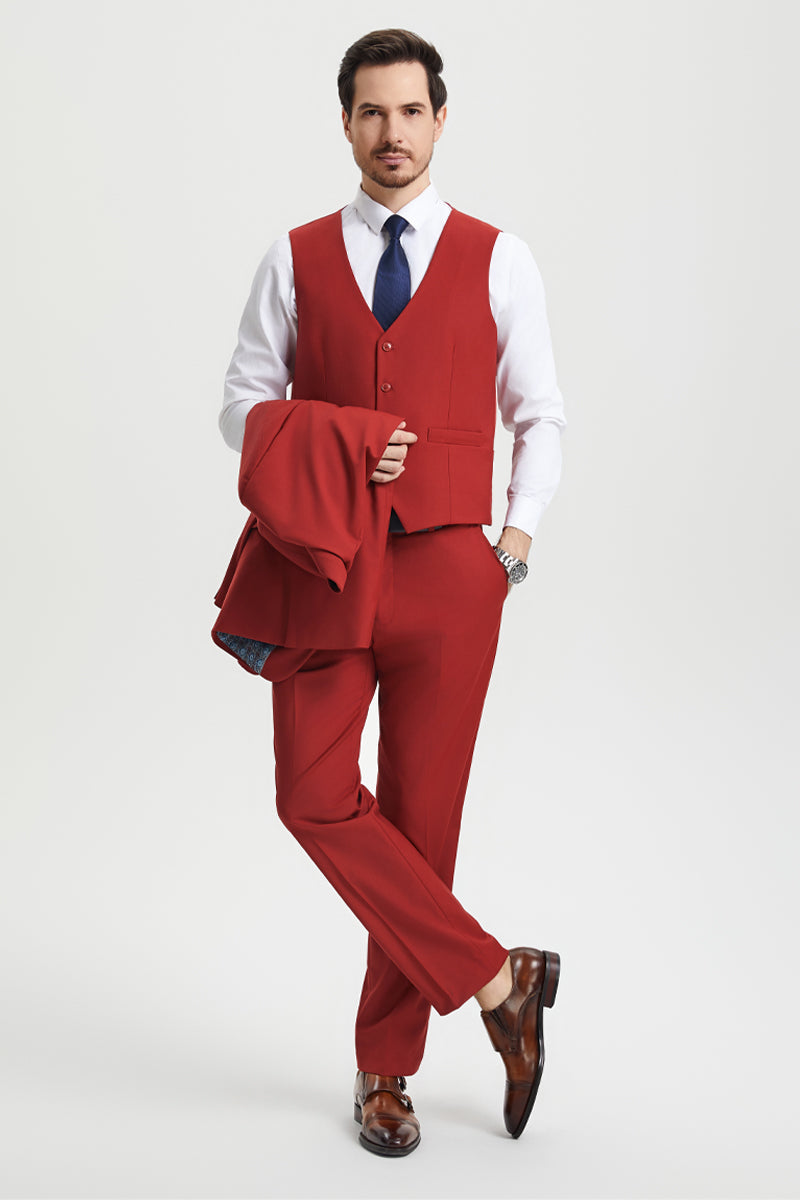 Stacy Adams brick-colored, two-button men's suit. Fitted vest, straight-leg trousers. Includes white shirt, navy tie, and brown polished shoes. Model holding jacket.
