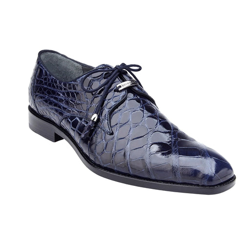 Navy alligator Lago dress shoe with plain toe and pointed silhouette. Features a scale pattern, lace-up design with navy laces. Contrasting black rubber sole.