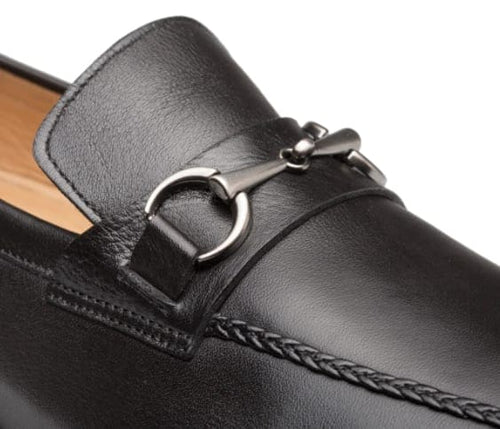 Black penny loafer: Smooth leather, rounded toe, metal bit accent, stitched edges, and braided vamp detail. Sleek design.
