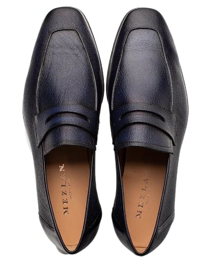 Blue deerskin penny loafers for men. Slip-on style with smooth surface and rounded toe. Decorative stitching and raised penny strap. Tan lined interior.