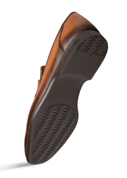 Men's cognac deerskin penny loafers. Smooth, rounded profile with a low heel. Crafted from cognac deerskin with a dark rubber sole and textured tread. Features a stitched penny slot.
