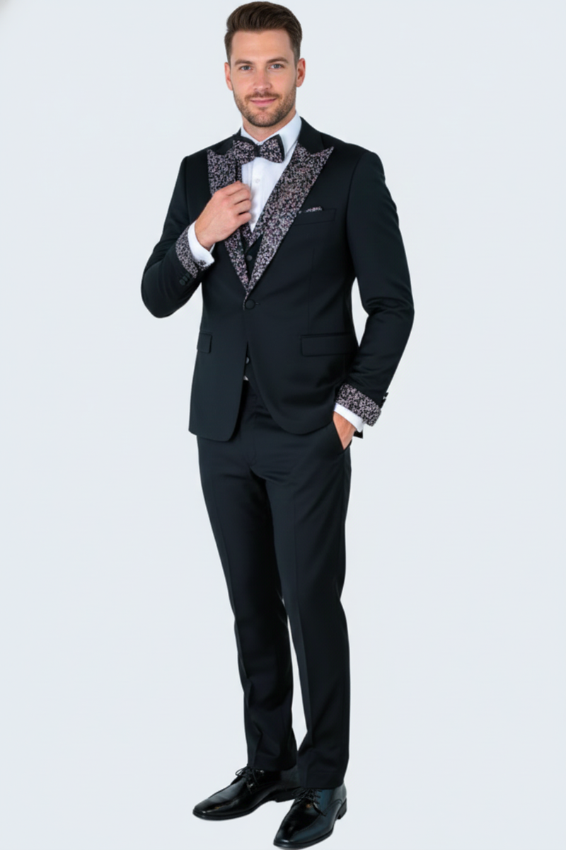 Black tuxedo with silver shawl lapel, single-button closure, tailored fit. Matching trousers, white shirt, patterned bow tie. White cuff detailing.