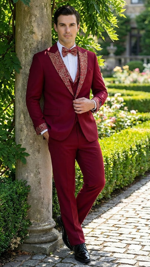 Men's burgundy tuxedo suit with white embellishments. Features a fitted silhouette, single-breasted jacket, and matching trousers. Embellished lapels and bow tie add contrasting detail. Polished and formal.
