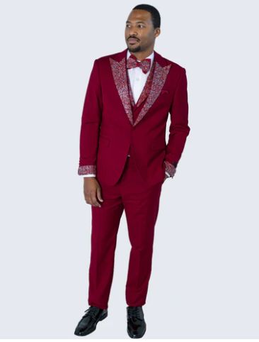 Burgundy tuxedo suit with white embellishments. Tailored jacket with decorated lapels and cuffs, plus matching fitted trousers. Classic style, refined look.