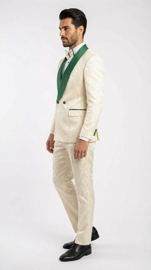 Ivory tuxedo suit with emerald green accents. Jacquard pattern, shawl collar, and two-button closure on jacket. Tailored ivory pants. Green pocket square. Black dress shoes complete the formal look.