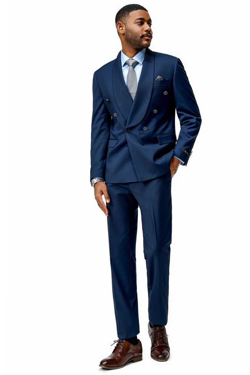Navy double-breasted men's suit with shawl lapels. Modern fit, tailored silhouette. Smooth texture, two rows of buttons. Paired with a light blue shirt, patterned tie, and brown shoes for a refined look.