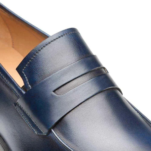 Mezlan navy penny loafer in burnished calfskin. Sleek, streamlined silhouette with rounded toe and decorative vamp strap. Subtle sheen and curved outsole.