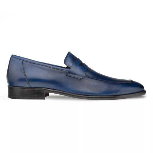 Navy Mezlan penny loafer in burnished calfskin. Sleek, elongated shape with a low profile. Features smooth, polished navy leather, an adjustable strap, and a rounded toe. Flat sole with a subtle heel.