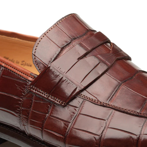 Tan Mezlan Piccolo Sport penny loafer in genuine alligator. Sleek, elongated shape with smooth upper, decorative penny strap, and textured alligator skin. Visible stitching enhances integrity.