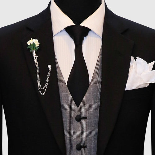 Black suit with a gray plaid vest. The suit jacket has a structured form and features a single-breasted design. The vest displays a plaid pattern in various shades of gray and is fitted, with three buttons visible at the front.