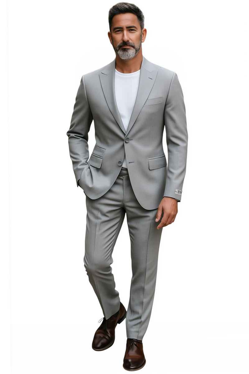 Men's Stacy Adams light grey slim fit suit. Structured blazer with notched lapel, two buttons. Matching slim trousers. Textured fabric with subtle pattern. Features visible pocket/seam detailing. Worn with a white shirt; trousers taper. Perfect for weddings/business.