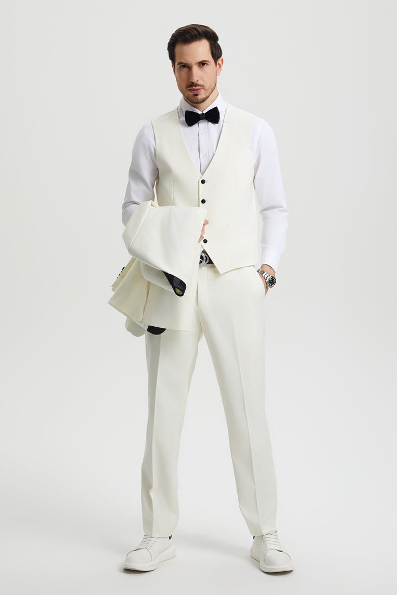 Ivory Stacy Adams one-button tuxedo with shawl lapel, matching vest and trousers. Features black button accents and cuff lining. Paired with a white shirt and sneakers for a tailored look.