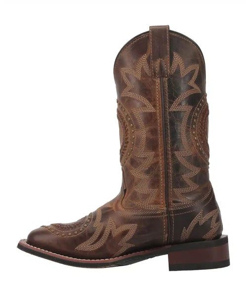 Laredo Charli women's boot: tall, brown leather, rounded toe, block heel. Intricate stitching, zigzag pattern, and decorative tooling enhance its Western style.