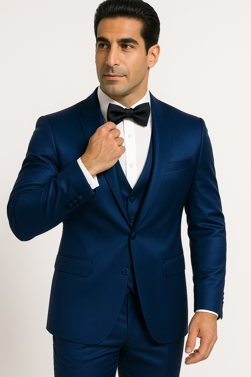 Blue Majesty tuxedo set: deep blue, shiny finish. Includes jacket (classic lapels, two buttons), waistcoat, trousers, and bow tie. Worn with a white dress shirt for a cohesive formal look.