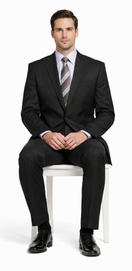 Carlo Lusso black two-button poly blend suit with tailored fit. Features notched lapel, side pockets, and straight-leg pants. Paired with a light purple shirt and patterned tie. Classic, formal look.