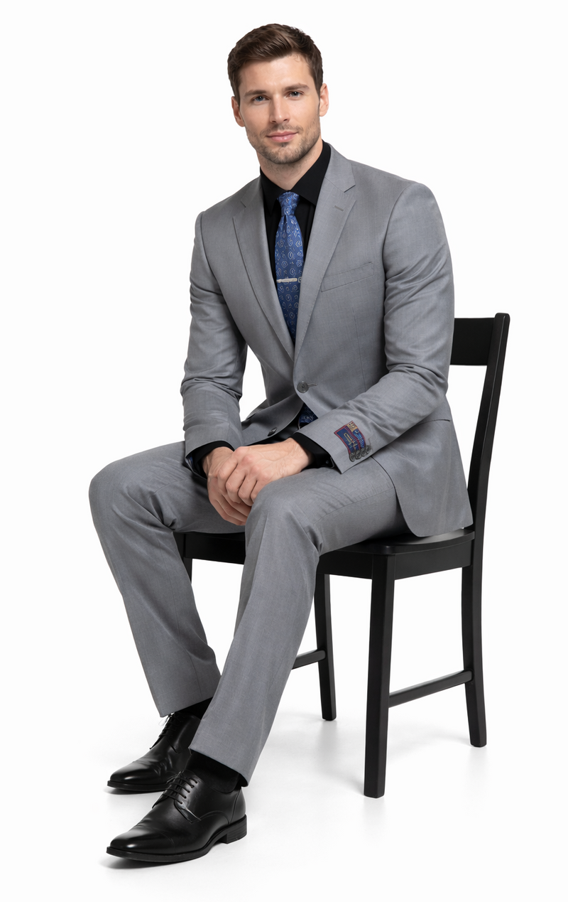 Carlo Lusso medium gray suit: tailored fit, poly blend with subtle pinstripe. Single-breasted jacket with notched lapel & patch pockets, contrasting cuffs. Straight leg trousers.