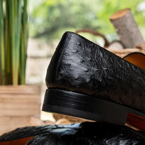 Black Mezlan Lisbon loafers: Rounded shape, flat heel. Textured black ostrich quill leather upper. Contrasting interior lining, black sole with edge ridge. Penny loafer style.