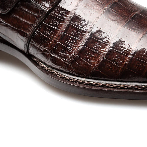 Brown Mezlan Gigolo monk strap. Sleek, elongated silhouette with textured brown crocodile leather upper. Single monk strap with metal buckle closure. Dark brown leather sole with stitch detailing. Rounded toe.