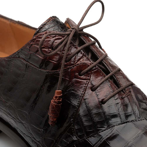 Mezlan Pueblo chocolate oxford sport shoe. Features: crocodile-textured, glossy leather upper, rounded toe, lace-up design with unique aglets, and visible stitching. Primarily dark chocolate color. High-quality craftsmanship.