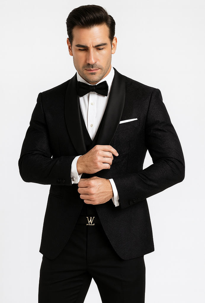 Elegant black floral lace tuxedo for men. Single-breasted jacket, shawl collar, matching vest. Floral lace pattern, tailored fit. Paired with white shirt, black bow tie, and trousers. Gold buckle belt.